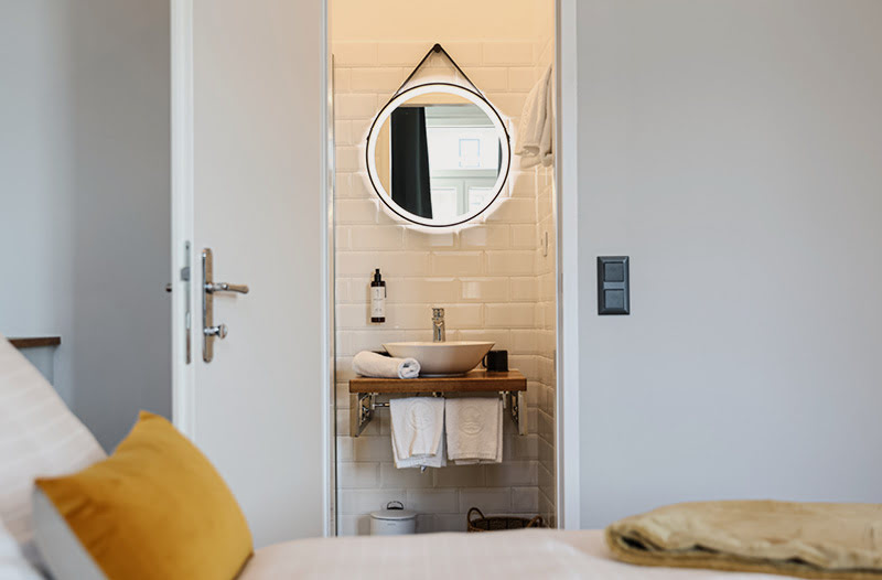 Im modern weiß gefliesten Bad erwartet Sie u.a. ein rundum beleuchteter Spiegel und Saint Charles Kosmetik.