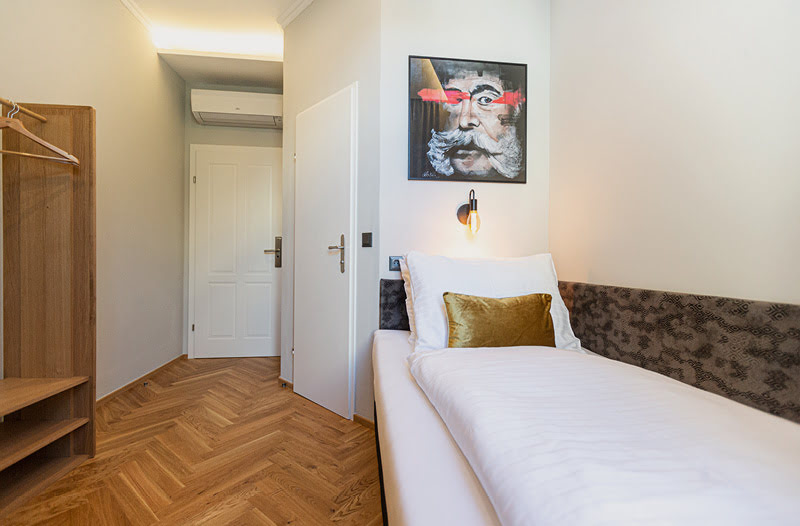 In dem klimatisierten Einzelzimmer hängt über dem Bett eine athmosphärische Lampe und ein modernes Kunstwerk mit Wien-Bezug.